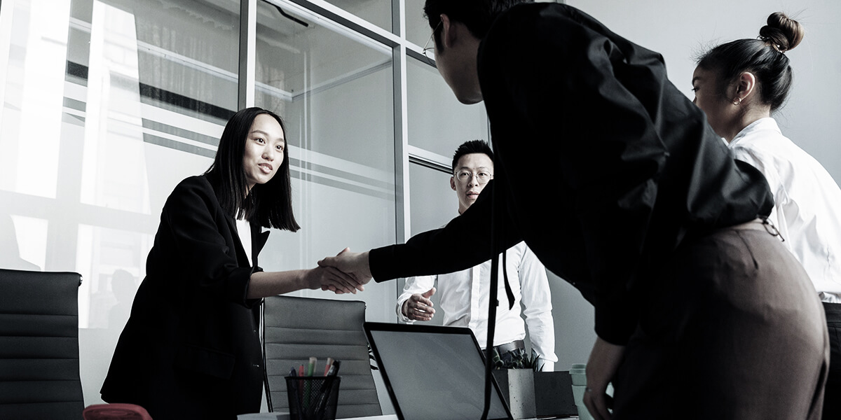 Two attorneys shaking hands in a modern office, representing a New York law firm during a professional meeting.